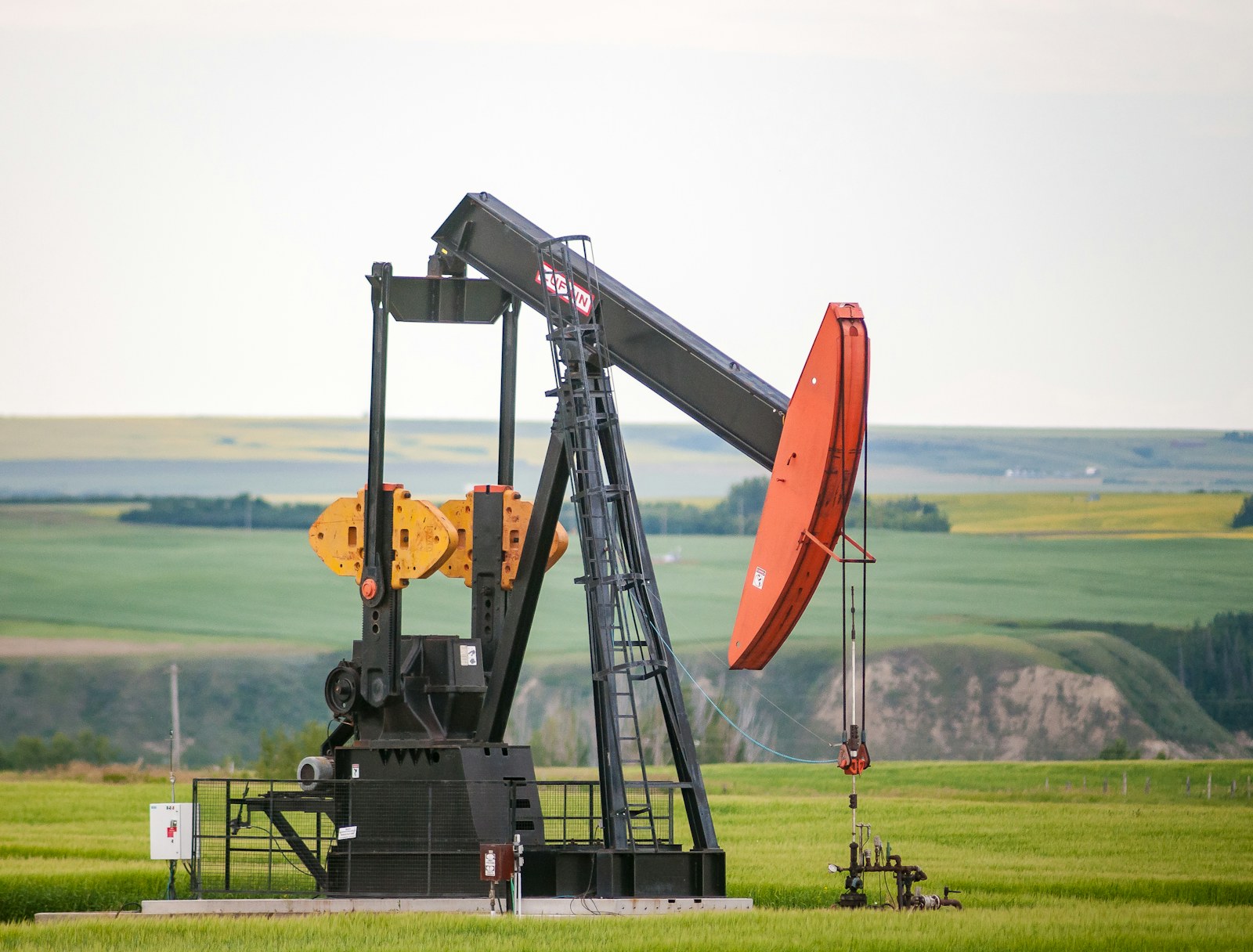 Oilfield pumpjack in a canola field, illustrative photo
